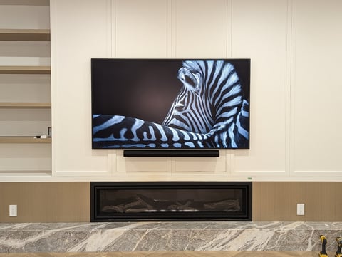 Modern living room with wall-mounted TV displaying zebra artwork above a linear fireplace with stone surround