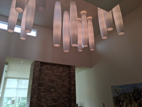 Modern pendant light fixture with multiple tubular glass shades hanging from ceiling in contemporary interior