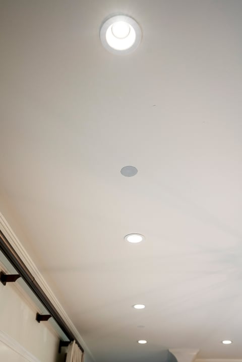 Ceiling with recessed lighting fixtures and a decorative light fixture with crescent moon design mounted on white drywall