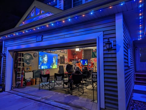 Garage converted into streaming studio at night, lit with blue LED strips, featuring gaming setup with monitors and equipment inside